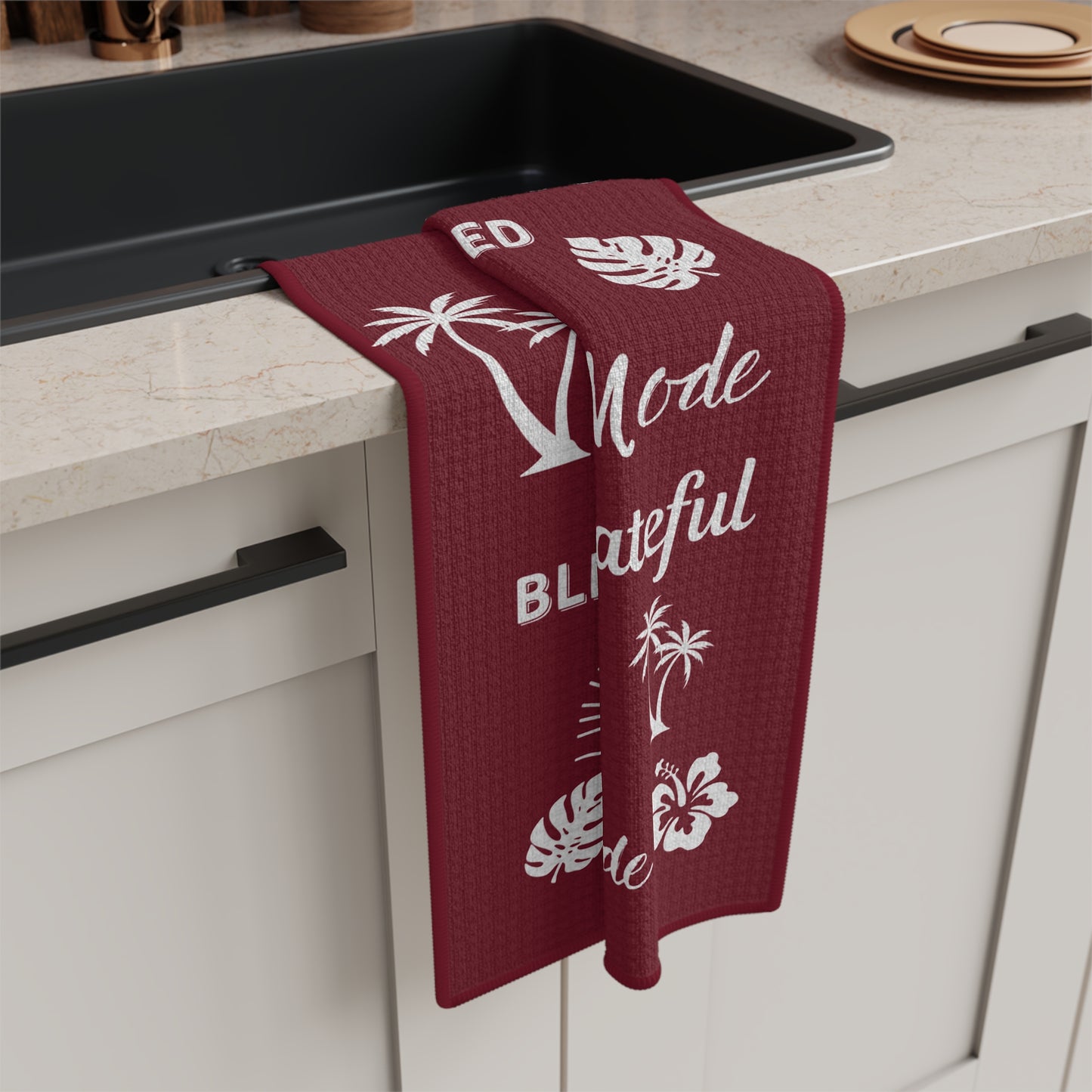 Burgundy Mahalo Mode kitchen towel with thankful grateful blessed and tropical island motifs hanging from a kitchen sink