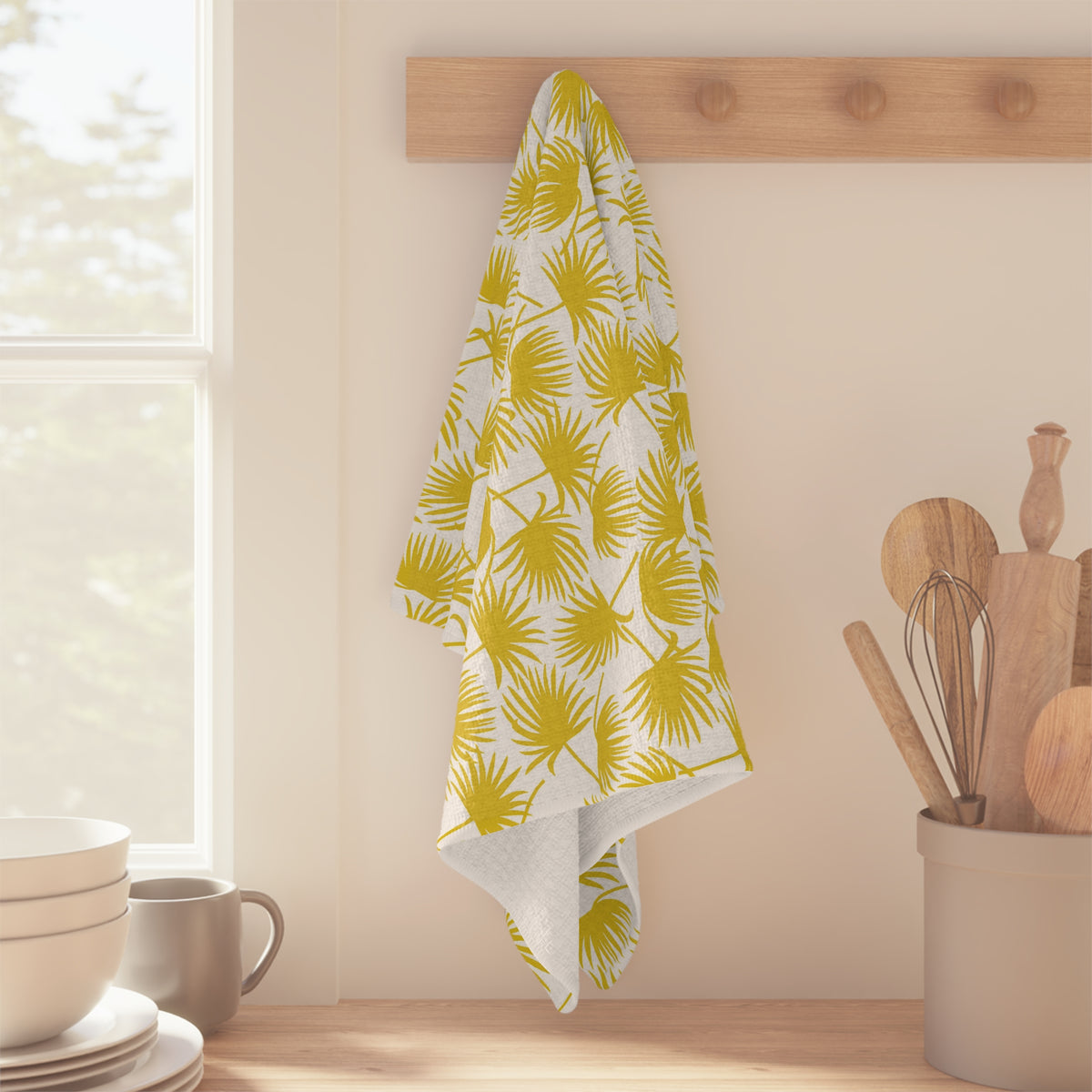 Fan Palm Sunshine kitchen towel with yellow tropical palm print by Global Village Kailua hanging off of wood peg in kitchen setting