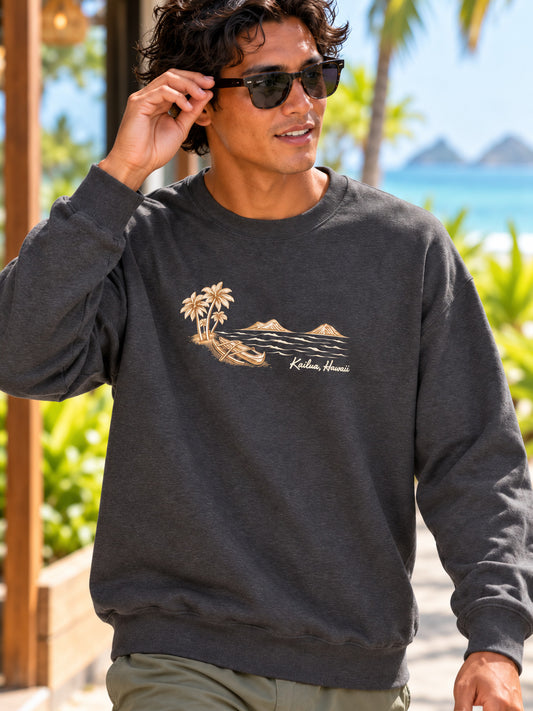 Surfer wearing a charcoal Kailua canoe and Mokulua Islands sweatshirt while adjusting his sunglasses near a tropical beach.