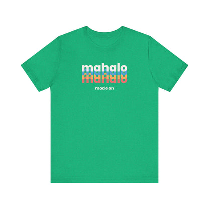 A green short-sleeve crewneck t-shirt with a retro-style chest graphic reading 'mahalo mode on' in white, blue, and orange lettering, displayed on a solid white background.