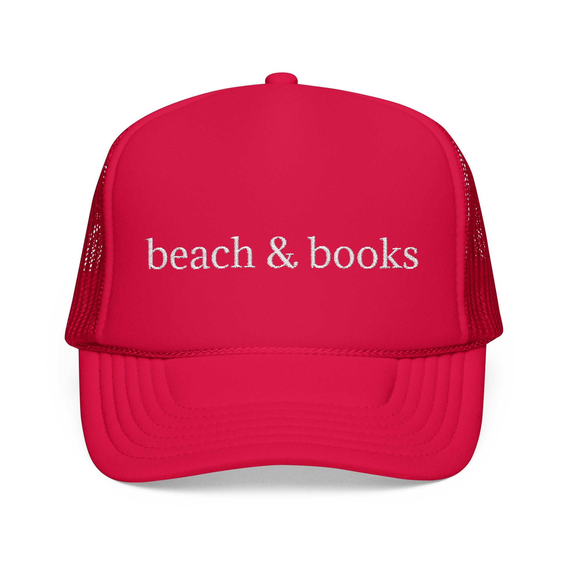 A bright red trucker hat with white embroidered text reading 'beach & books' on the front, shown against a plain white background.