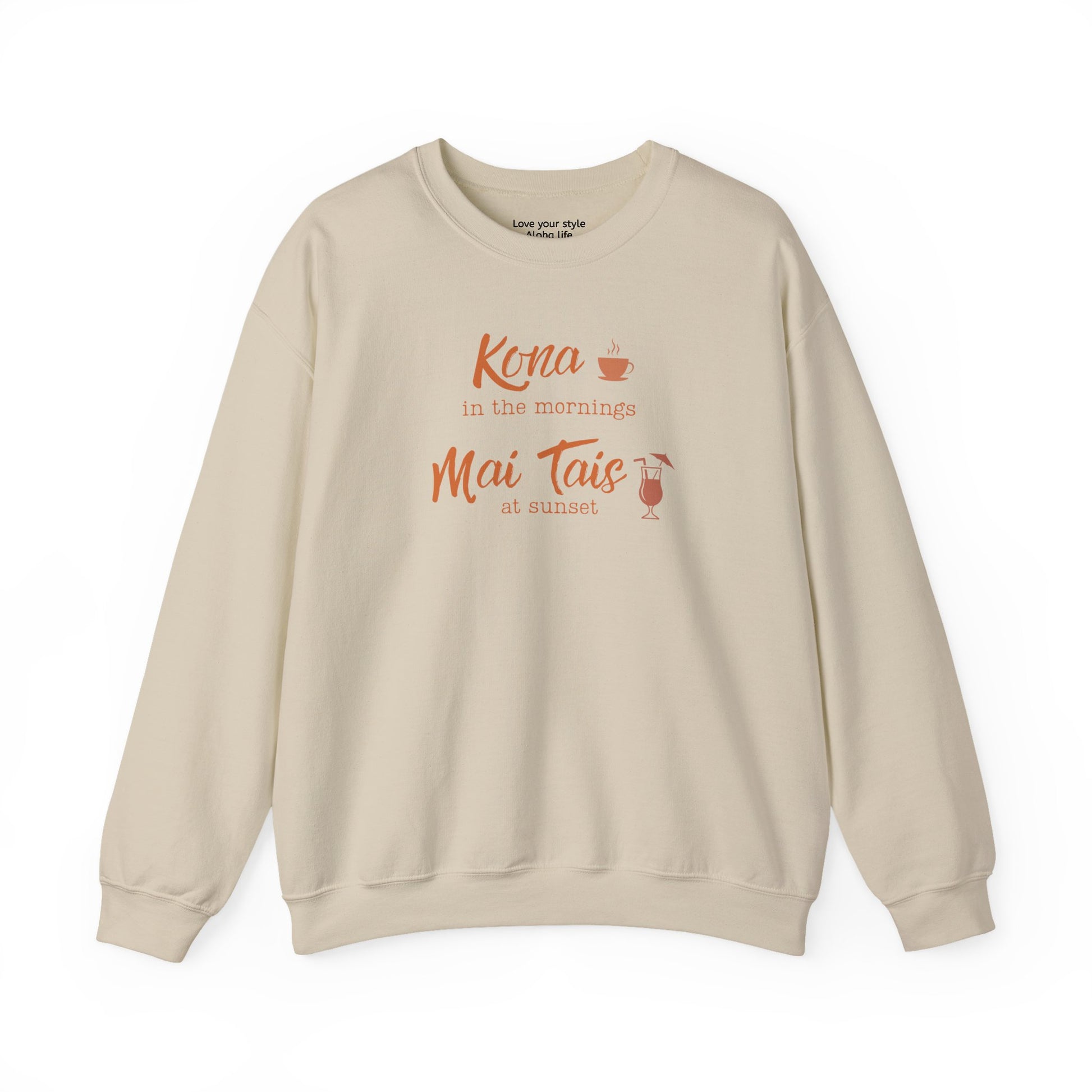 A sand crewneck sweatshirt with a coral orange graphic print on the front that reads 'Kona in the mornings Mai Tais at sunset' with a small coffee cup and cocktail glass illustration.