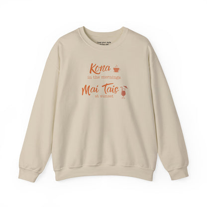 A sand crewneck sweatshirt with a coral orange graphic print on the front that reads 'Kona in the mornings Mai Tais at sunset' with a small coffee cup and cocktail glass illustration.
