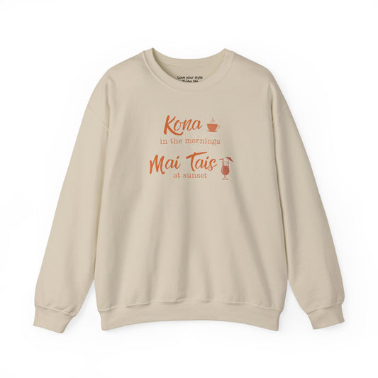 A sand crewneck sweatshirt with a coral orange graphic print on the front that reads 'Kona in the mornings Mai Tais at sunset' with a small coffee cup and cocktail glass illustration.
