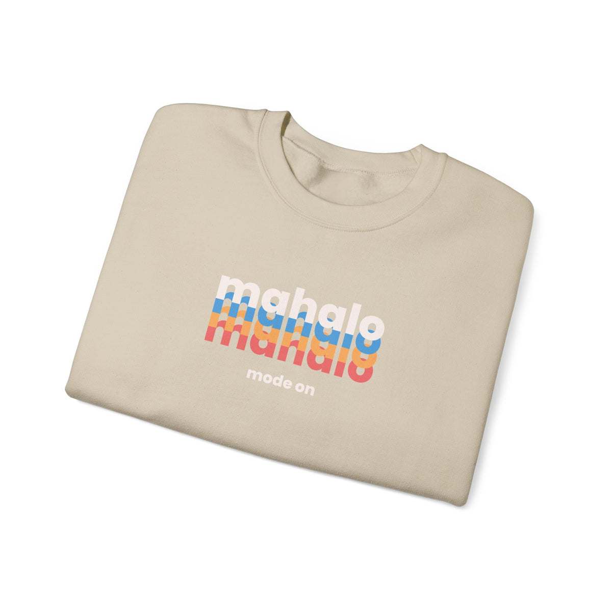 A folded beige crewneck t-shirt with a retro-style graphic on the chest. The graphic features the word 'mahalo' repeated in white, blue, orange, and red wavy stripes, with 'mode on' printed below in white.