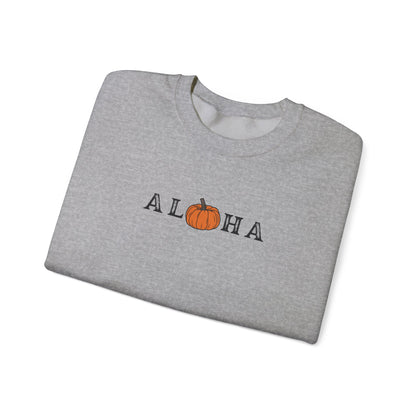 A folded heather gray crewneck sweatshirt featuring the word 'ALOHA' printed across the chest, with the letter 'O' replaced by a small orange pumpkin graphic, shown on a plain white background.
