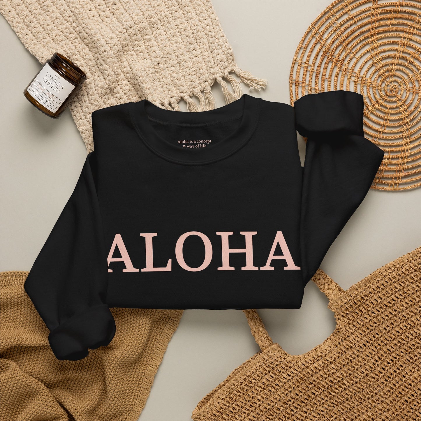 Black sweatshirt folded with text 'ALOHA' in light pink