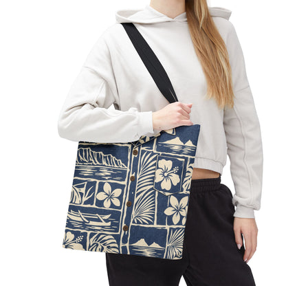 A woman wearing a white cropped hoodie and black sweatpants carries a large navy blue tote bag with a cream tropical floral and wave print. The bag has a black shoulder strap and visible brown buttons on the front pocket.