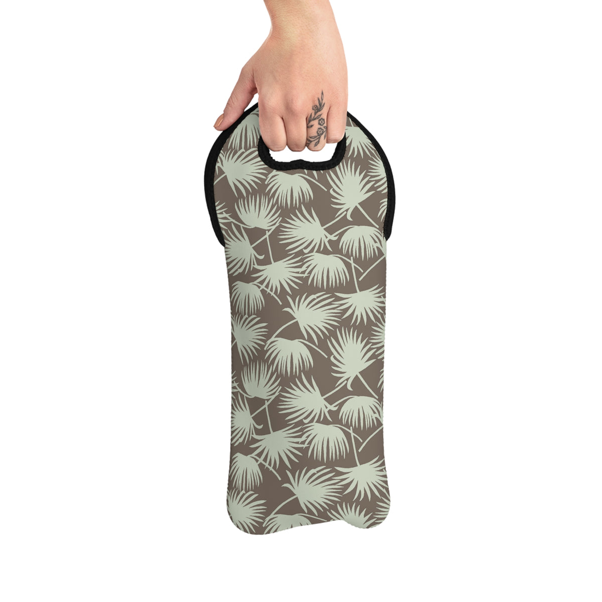 A hand holding a soft-sided sleeve or pouch with a palm leaf pattern in muted sage green and taupe, shown against a plain white background.