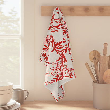 Red and white coral print Hawaiʻi kitchen towel with original Global Village pattern hanging off a wood peg in the kitchen