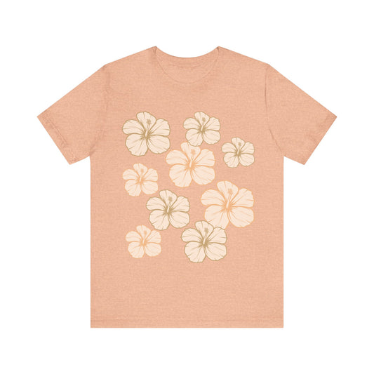 Soft peach Hibiscus All Over Graphic Tee featuring scattered tropical hibiscus flowers on a soft unisex tee inspired by island life in Hawaii.
