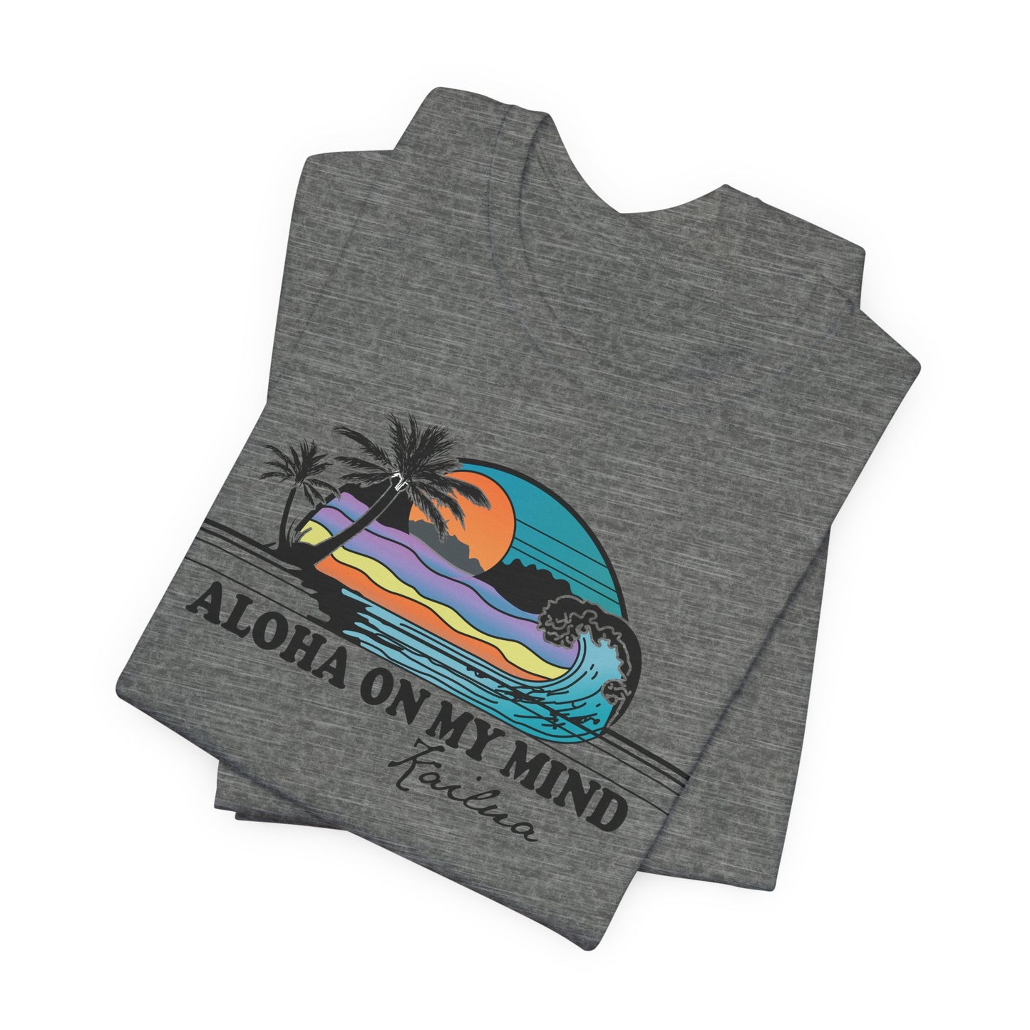 A folded heather gray t-shirt with a colorful retro graphic of a Hawaiian sunset and wave, featuring the text 'ALOHA ON MY MIND' and 'Kailua' underneath, displayed on a clean white background.