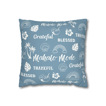 A square throw pillow in dusty blue with a white tropical-themed print featuring palm trees, hibiscus flowers, seashells, sunsets, and words like 'Mahalo Mode', 'Grateful', and 'Blessed'.