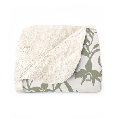 Folded Sage green orchid-and-leaf print sherpa fleece blanket with a warm white background and rounded corners.