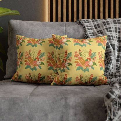 A rectangular throw pillow with a vibrant yellow background and a detailed tropical floral pattern in orange, green, and red, styled on a gray sofa next to a black and white plaid throw blanket.