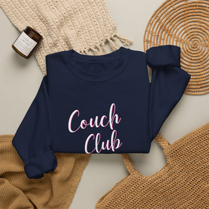 Folded navy sweatshirt with a graphic design text 'Couch Club' on a textured surface