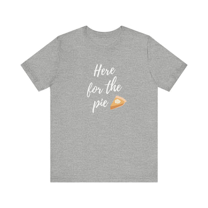 A heather gray short-sleeve t-shirt with a graphic on the chest that reads 'Here for the pie' in white script, accompanied by a small slice of pumpkin pie illustration.