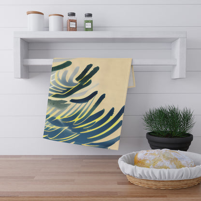 A kitchen towel with a tropical palm leaf pattern in navy blue, green, and yellow on a cream background, hanging from a white wall-mounted rack in a bright kitchen setting.