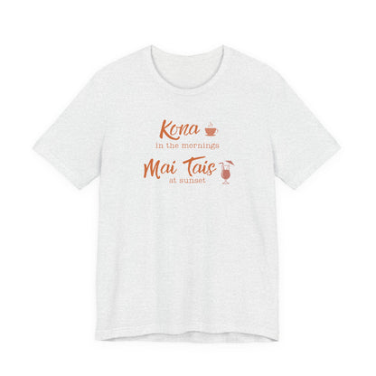 An ash short-sleeve crewneck t-shirt with a coral orange graphic on the chest that reads 'Kona in the mornings Mai Tais at sunset' with small coffee and cocktail illustrations.