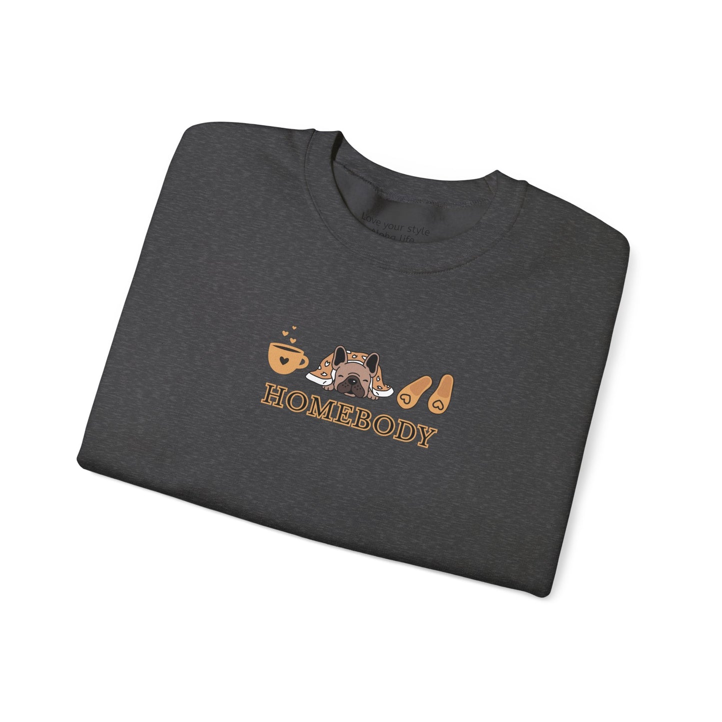 A folded dark grey crewneck sweatshirt featuring a central graphic of a dog under a blanket, house slippers, coffee cups and the word 'HOMEBODY' printed below it.