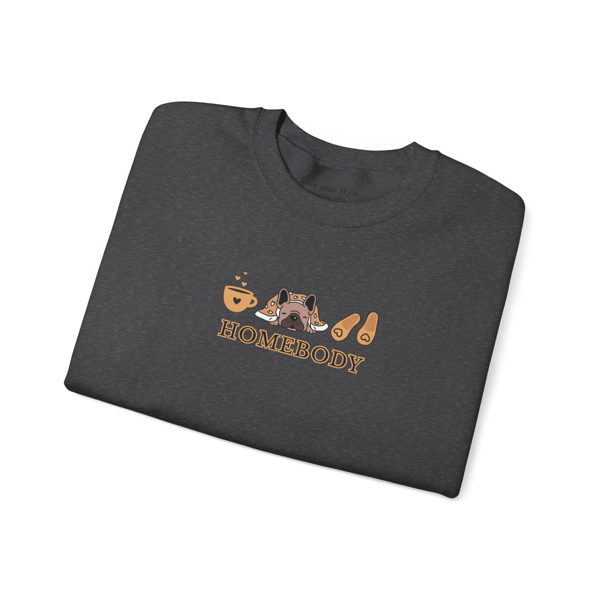 A folded dark grey crewneck sweatshirt featuring a central graphic of a dog under a blanket, house slippers, coffee cups and the word 'HOMEBODY' printed below it.