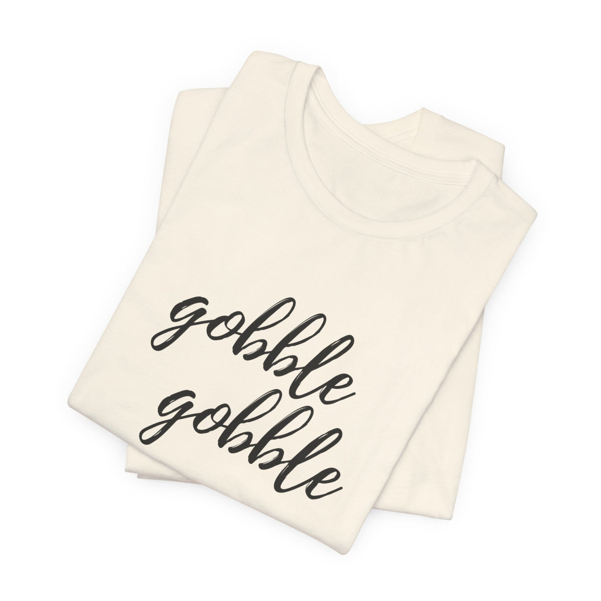 A folded cream-colored t-shirt with the phrase 'gobble gobble' printed in black cursive script across the front, displayed on a clean white background.
