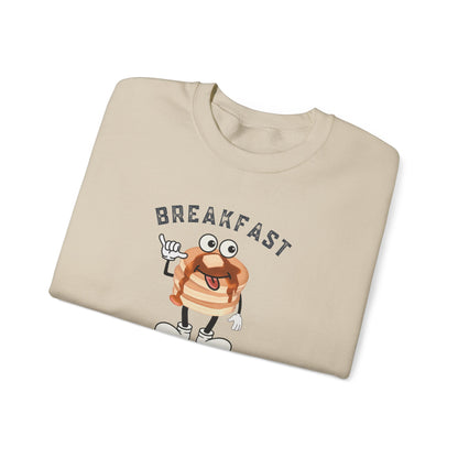 A beige crewneck sweatshirt with a cartoon pancake graphic and the word 'BREAKFAST' printed on the front, shown folded on a white background.