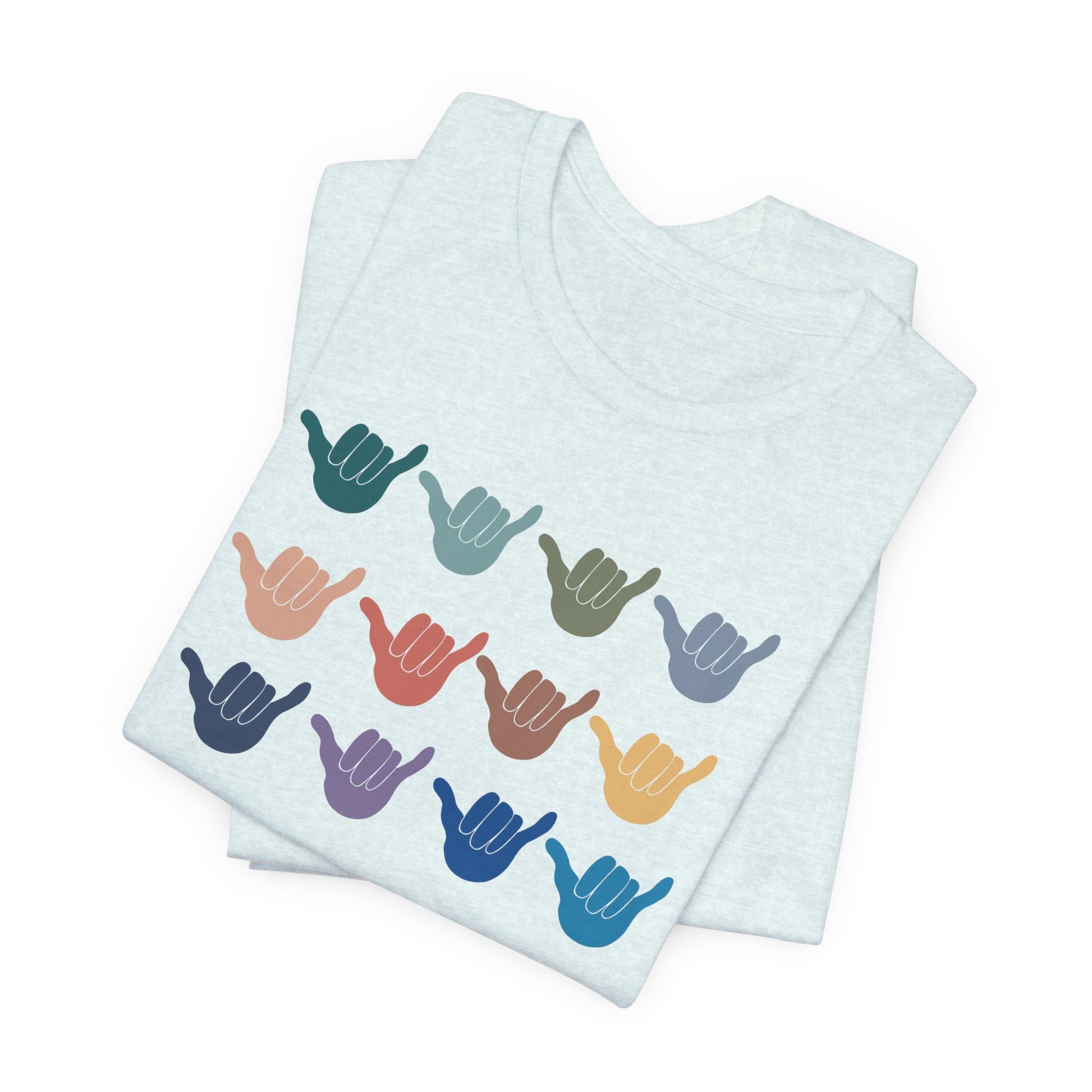 A folded light blue t-shirt featuring a grid of colorful shaka hand signs on the front, displayed on a clean white background.