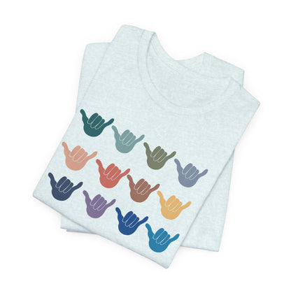 A folded light blue t-shirt featuring a grid of colorful shaka hand signs on the front, displayed on a clean white background.