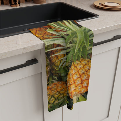 A kitchen towel with a realistic pineapple print hangs over the edge of a black sink in a modern kitchen setting.