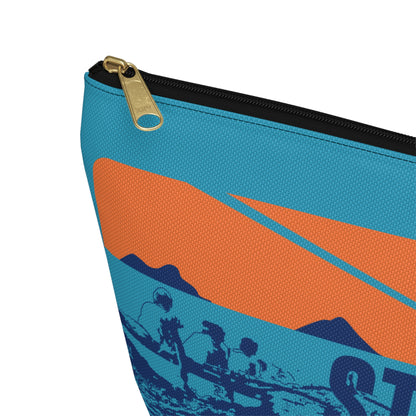 A close-up of a zippered pouch or bag corner showing a blue and orange graphic print with a black zipper and a gold-tone zipper pull on a white background.