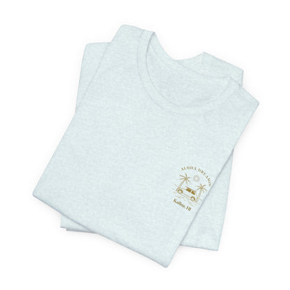 A folded light blue short-sleeve t-shirt shown from the front, featuring a gold-colored retro graphic of a classic car between two palm trees with the text 'ALOHA DREAMIN'' and 'Kailua, HI' on the left chest.