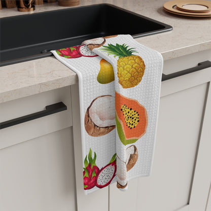 A white kitchen towel with a colorful tropical fruit print, draped over the edge of a black sink in a modern kitchen setting.