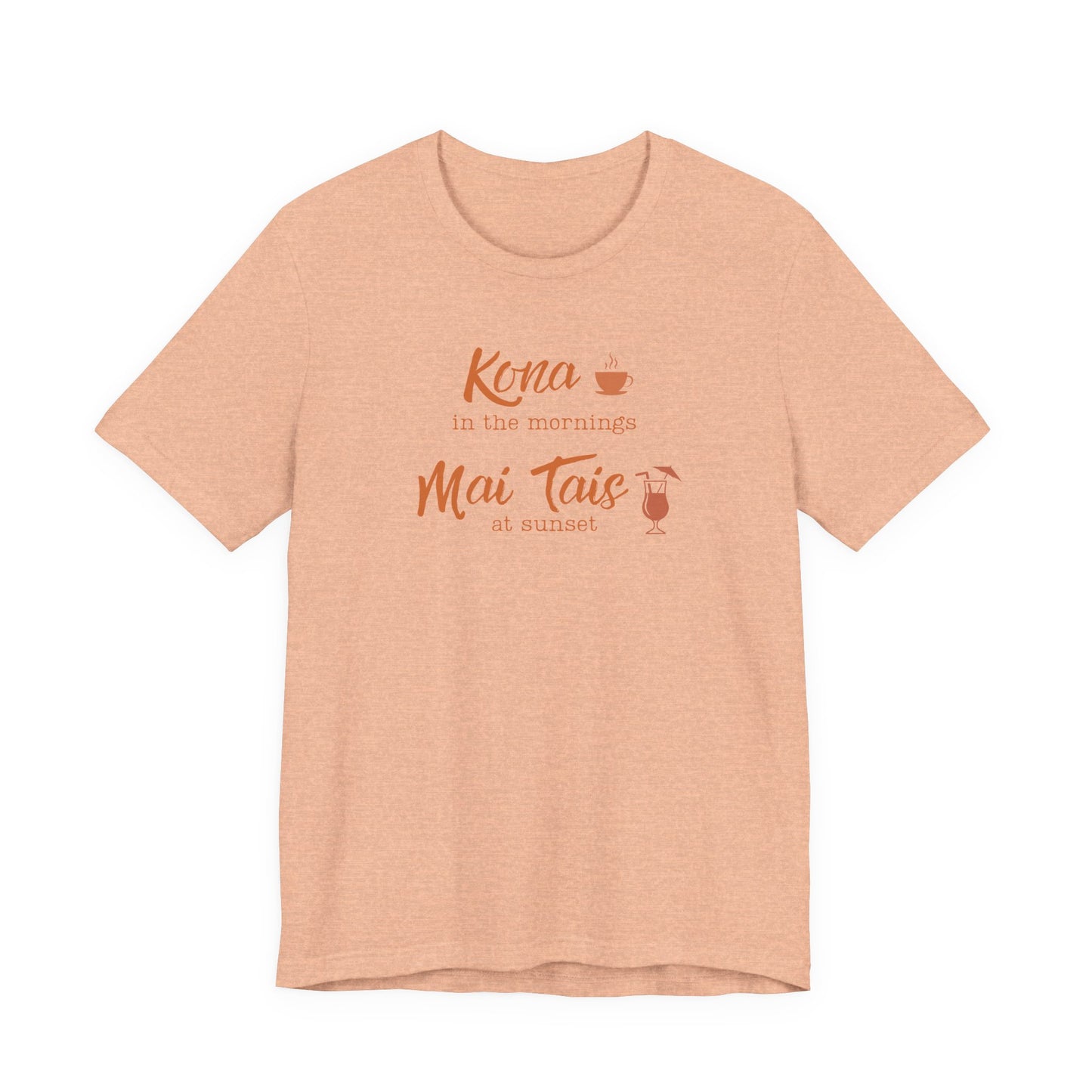 A heather peach short-sleeve t-shirt with a coral orange graphic on the chest that reads 'Kona in the mornings Mai Tais at sunset' with small coffee and cocktail illustrations, displayed on a clean white background.