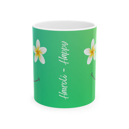 A green ceramic mug with a white interior, decorated with two white plumeria flowers and the words 'Hauʻoli - Happy' in white script.