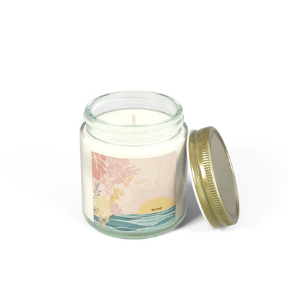 A glass jar candle with cream-colored wax, a tropical sunset label, and a gold metal screw-on lid resting beside it on a white background.