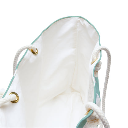 Close-up of the interior of a white drawstring bag with mint green piping, white rope handles, and gold-tone metal grommets on a white background.