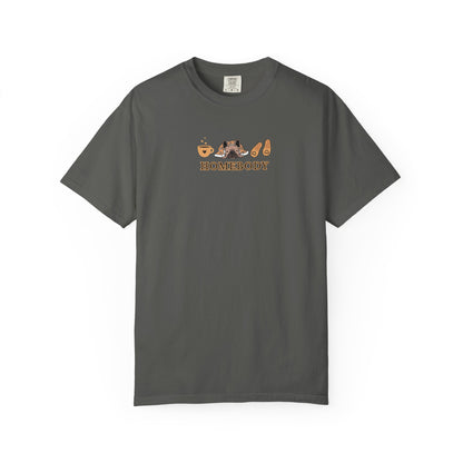 An dark grey short-sleeve crewneck t-shirt with a graphic on the chest depicting a dog under a blanket, a coffee mug, a pair of house slippers, and the word 'HOMEBODY' in brown text.
