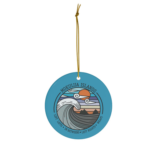 Blue ceramic ornament with Mokulua Islands surf design featuring a curling wave, sunset and Nā Mokulua off Kailua, Hawaiʻi.