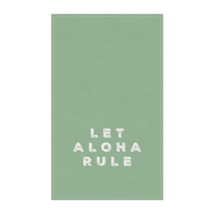 A rectangular sage green tea towel with the phrase 'LET ALOHA RULE' printed in white block letters near the bottom center, shown against a plain white background.