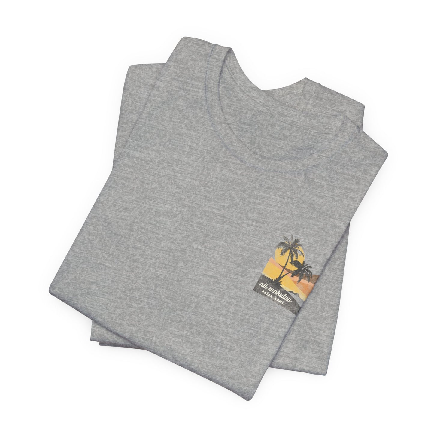 A heather grey short-sleeve t-shirt with a vintage-style graphic on the front left chest depicting two palm trees against a yellow and orange sunset, with the text 'ná makulua' and 'Kailua, Hawaii!' printed below.
