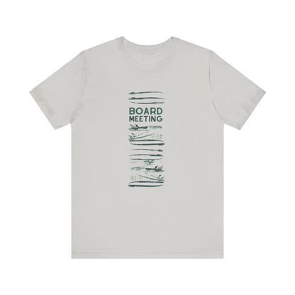 A light gray crewneck t-shirt with a dark green graphic on the front featuring the text 'BOARD MEETING' surrounded by horizontal surfboard patterns.