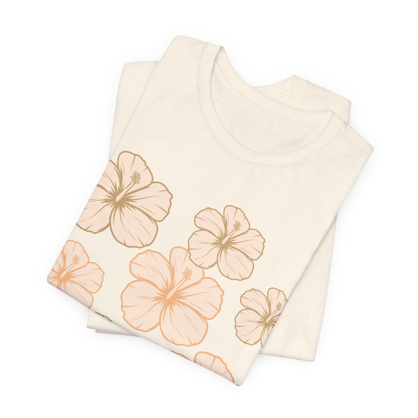 A folded cream-colored t-shirt featuring a pattern of large peach and light orange hibiscus flowers with brown outlines, displayed on a clean white background.