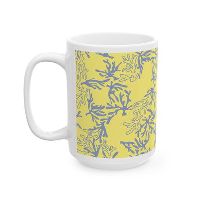 A white ceramic mug featuring a yellow and blue coral pattern wrap around its body, shown on a clean white background.