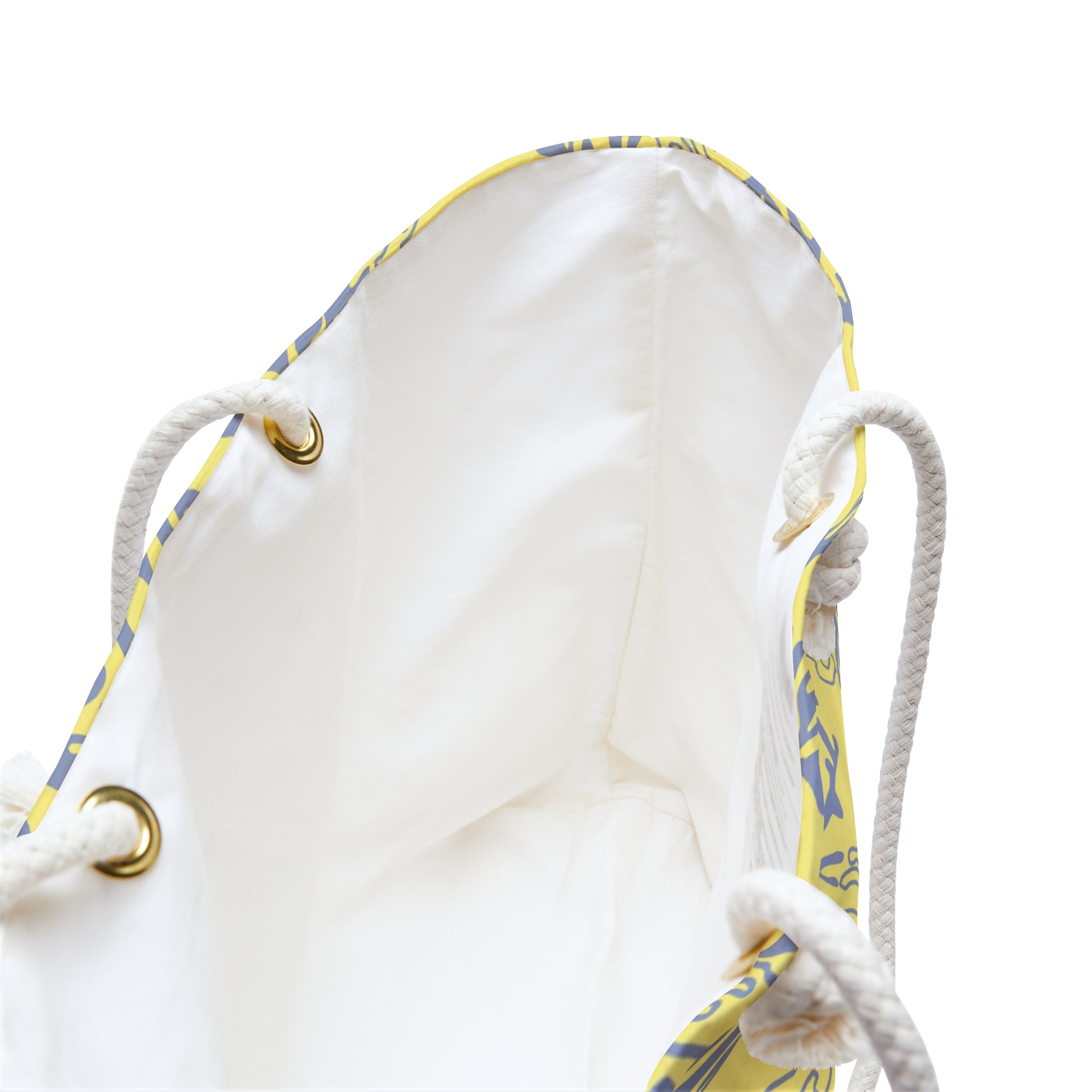 Close-up of a white drawstring bag showing the inner lining, white rope handles, gold-tone metal grommets, and a yellow and blue patterned trim along the opening.