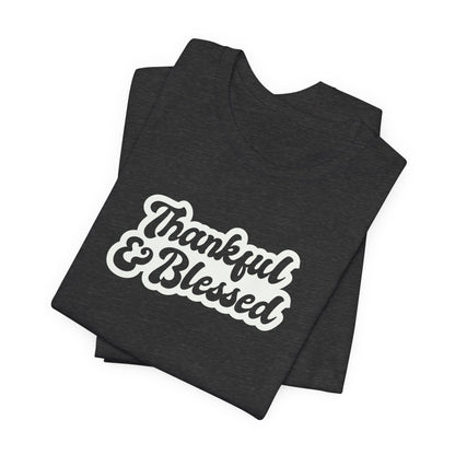 A folded black t-shirt with 'Thankful & Blessed' printed in a white and brown retro-style font, displayed on a clean white background.