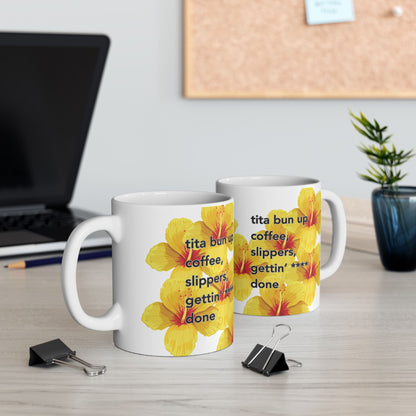 Two Tita Bun coffee mugs with yellow hibiscus design by Global Village Kailua sitting on a desk top with paper clips.