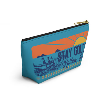 A rectangular zippered pouch with a retro sunset graphic on a teal background. The design features an orange and yellow sun, mountains, a fishing boat with two figures, and the text 'STAY GOLD' and 'Kailua, HI'.