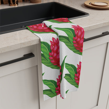 Red ginger Hawaiʻi kitchen towel with bright red tropical flowers and green leaves on white hanging off a kitchen sink
