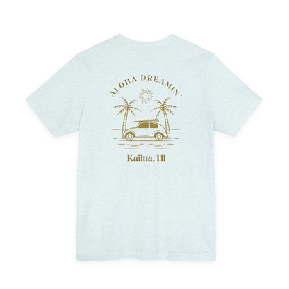 A light heather blue short-sleeve t-shirt shown from the back, featuring a retro-style tan graphic of a car between two palm trees with the text 'ALOHA DREAMIN'' and 'Kailua, HI'.